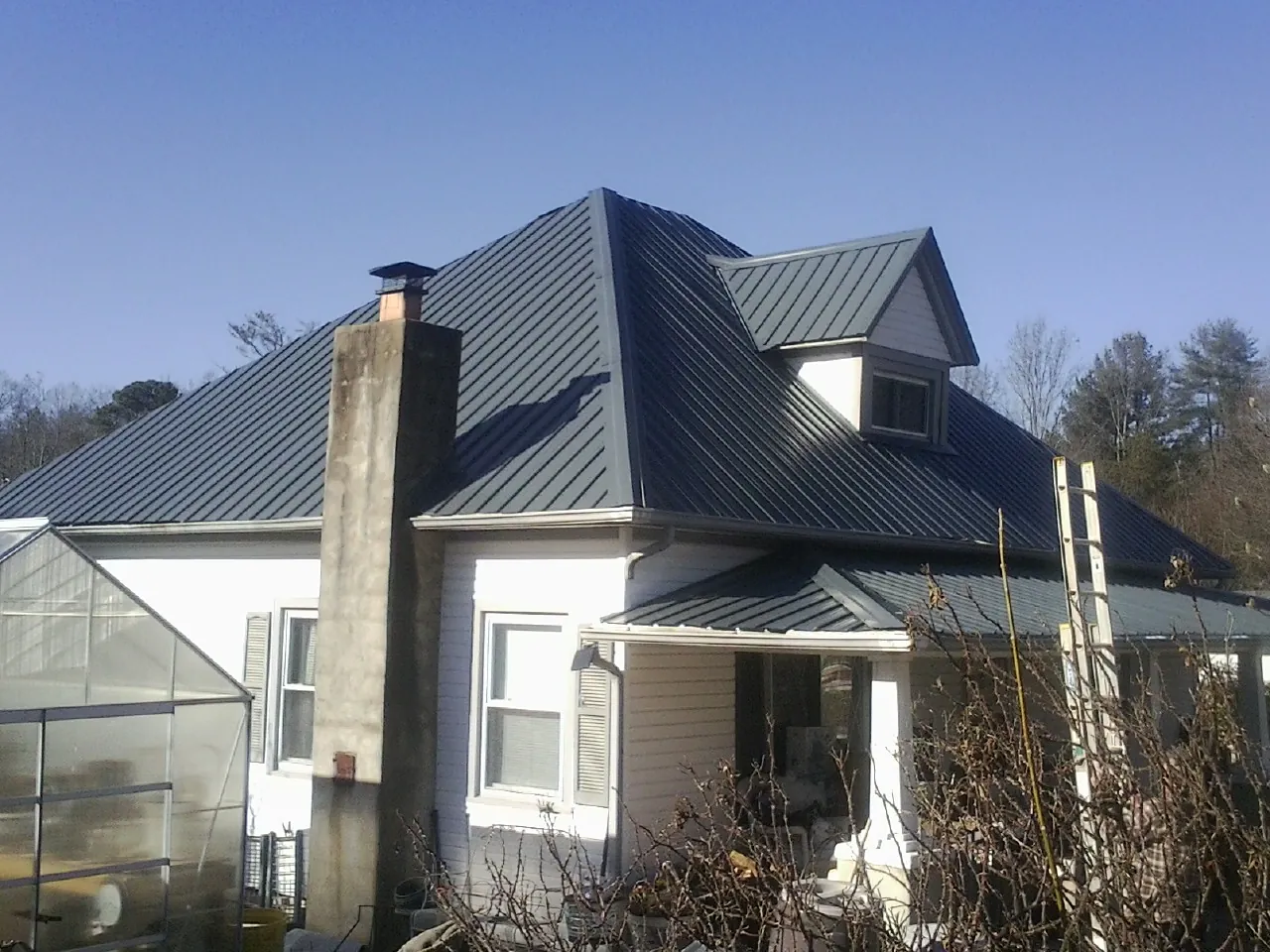 Dark blue standing seam metal roof on a white farmhouse with dormer — Slate & Tile Roof Repair by Roofing Brothers in Albrightsville