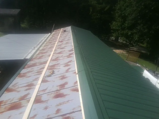 Old rusted panels beside newly installed green metal roofing — Wind Damage Roof Repair by Roofing Brothers in Albrightsville