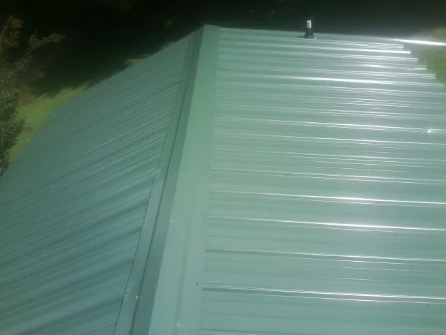 New green metal panels meeting at the ridge of a roof — Flat Roof Repair work by our crew in Albrightsville