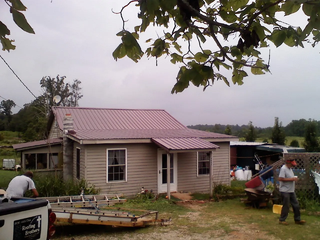 Crew finishing a mauve metal roof on a small farmhouse in Albrightsville