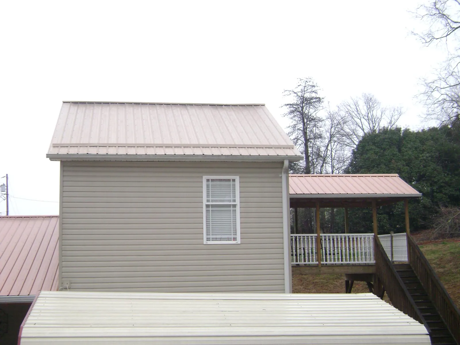 Tan metal roofs on a two story addition and attached porch, from a Roof Replacement job in Albrightsville