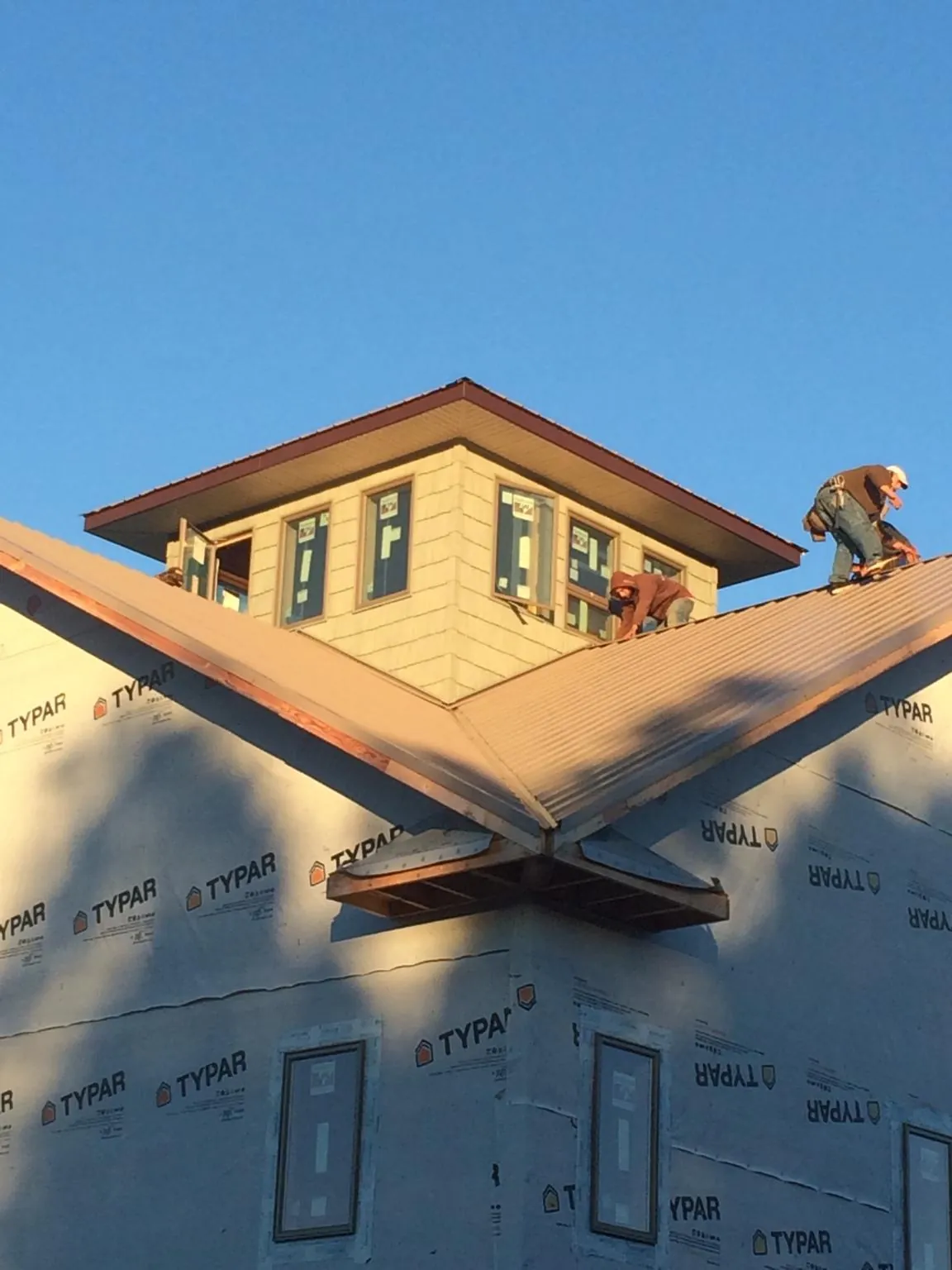 Roofers working around a rooftop cupola on a new metal roof at sunset — Roof Waterproofing in Albrightsville by Roofing Brothers